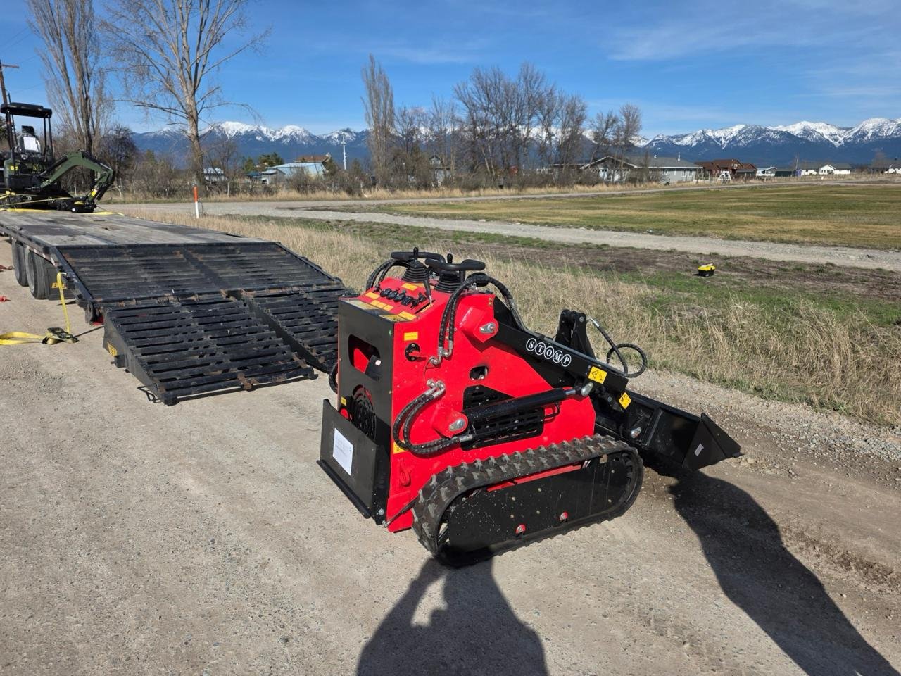 Red compact mini skid steer with bucket on a prepared surface