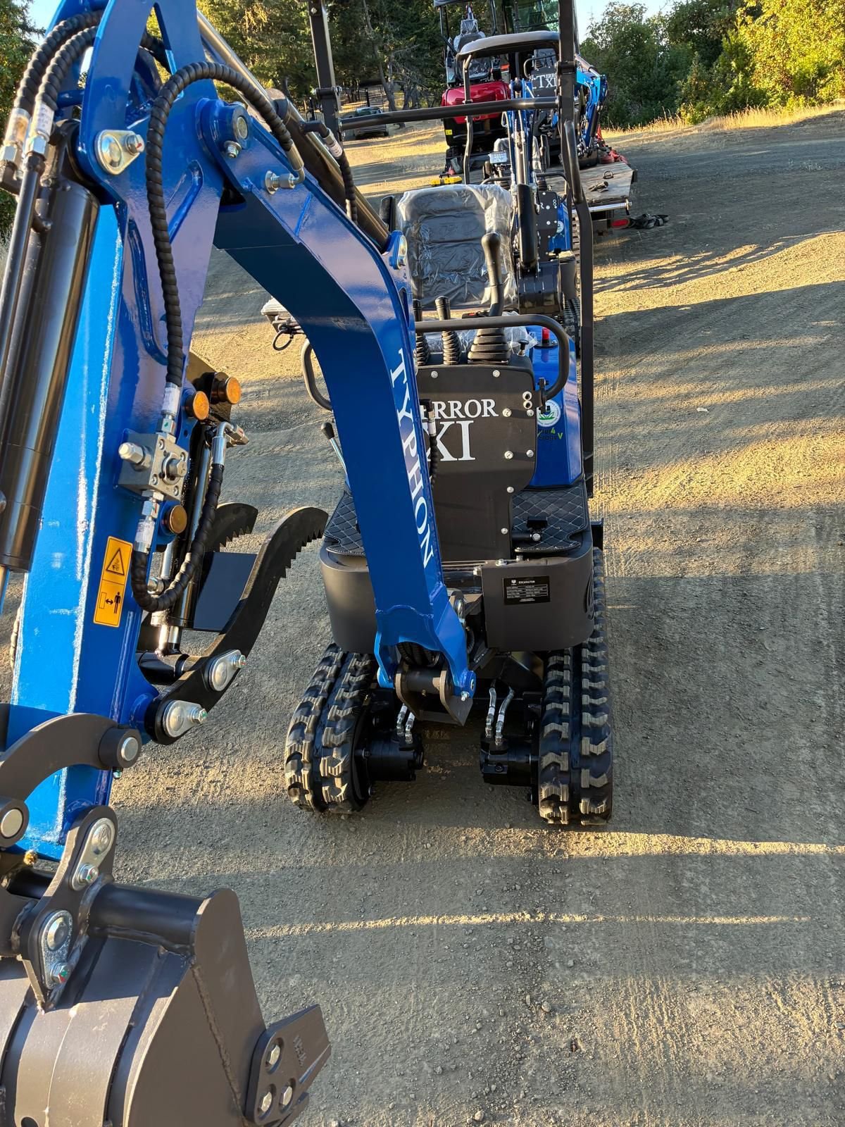 Blue TYPHON mini excavator positioned for roadside work